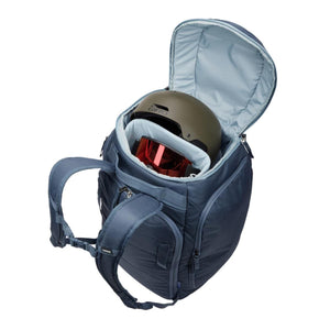 Thule blue backpack with open top compartment containing a Giro helmet and ski goggles
