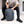 Person sitting while holding a grey Thule backpack