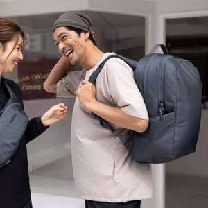 Man wearing a dark blue Thule backpack and a woman wearing a Thule sling bag