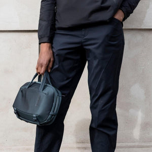 Person holding a dark Thule travel organizer by the top handles