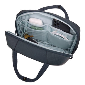 Open dark grey travel pouch with internal mesh pockets containing a phone, earbuds, keys, and charging cable