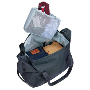 Thule duffel bag with open main compartment containing folded clothing and a mesh packing cube