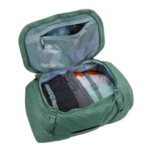 Open green Thule duffel bag packed with folded clothing and internal mesh storage pocket