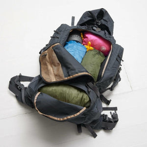 Open black hiking backpack packed with colorful gear and sleeping bags