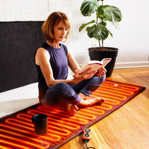 Woman sitting on a ToastiMat heated mat reading a book