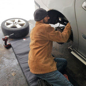 Person kneeling on a ToastiMat while performing car maintenance