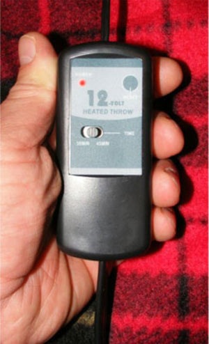 Trillium Worldwide 12 volt heated throw controller held in hand