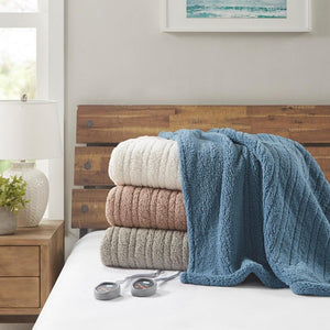 True North by Sleep Philosophy heated blankets stacked on a bed with remote controls