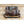 Camo hand warmer muff with Saskatchewan Original branding and black adjustable strap on wooden surface