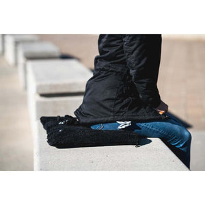 Person sitting on a black Tubes Canada fleece seat cushion on a concrete bench