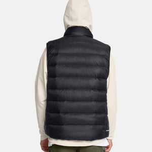 Back view of a person wearing a black Under Armour puffer vest over a beige hooded sweatshirt