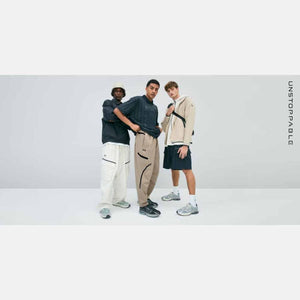 Three men wearing Under Armour apparel and sneakers standing against a plain background