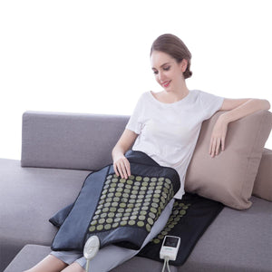 Woman sitting on a sofa using a UTK Technology infrared heating pad with jade stones