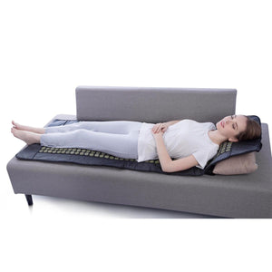 Person lying on a UTK Technology infrared heating mat on a grey sofa