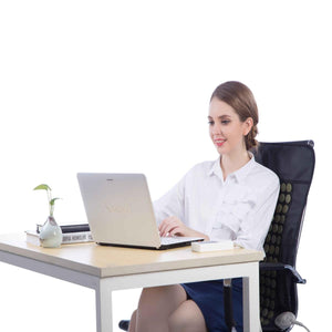 Woman sitting at a desk using a laptop with a UTK Technology heating pad on her office chair