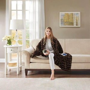 Woman sitting on a couch wrapped in a dark brown faux fur electric heated throw blanket