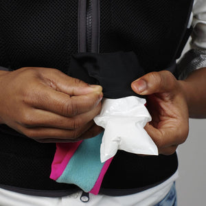Hands inserting a white cooling pack into a black fabric pocket on a vest