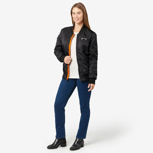 Woman wearing a black Venture Heat bomber jacket with orange lining over a white shirt and blue jeans