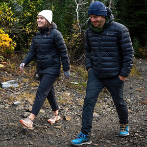 Two people wearing Venture Heat black puffer jackets walking on a rocky forest trail