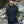 Man wearing a black Venture Heat vest over a green sweater outdoors