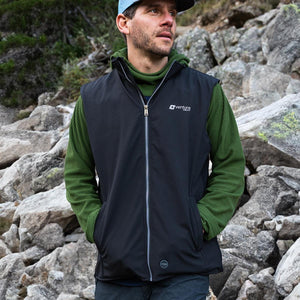 Man wearing a black Venture Heat vest over a green sweater outdoors