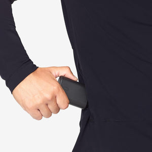 Hand placing a Venture Heat battery pack into a side pocket of a black long sleeve shirt