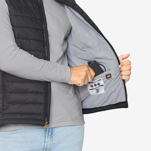 Person placing a Venture Heat battery pack into the interior pocket of a black heated vest
