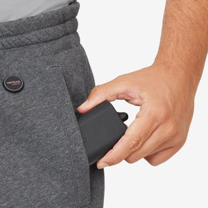Hand placing a Venture Heat battery pack into the pocket of grey sweatpants