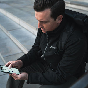 Person wearing a Venture Heat jacket using a smartphone app to control temperature settings