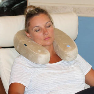 Woman wearing a beige Volt Heat neck pillow while resting in a chair