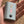 Grey portable battery pack with four red LED indicator lights and a power button held in a hand