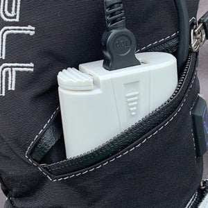 White power bank connected to a charging cable inside a black backpack pocket