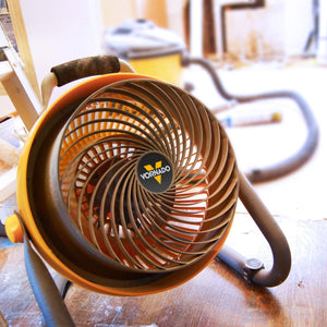 Vornado yellow and black utility air circulator fan on a wooden floor