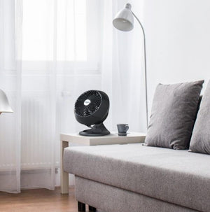 Vornado black air circulator fan on a side table next to a grey sofa