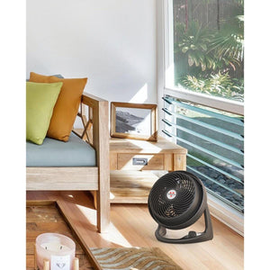Vornado black air circulator fan on a wooden floor next to a sofa