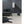 Black Vornado heater on a light floor next to a black leather sofa