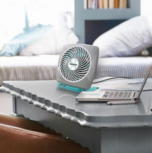 Vornado grey and teal desk fan on a table next to a laptop