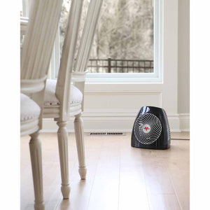 Black Vornado space heater on a wooden floor near a window