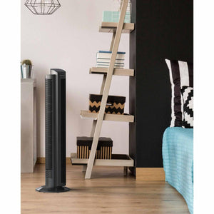 Vornado black tower fan standing on a wooden floor in a bedroom