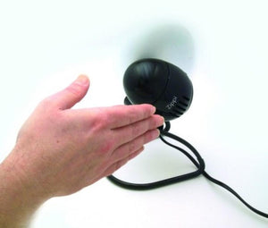 Hand held near a black Vornado Zippi personal fan