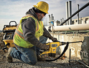 Construction worker using a DeWalt rotary hammer drill on a concrete wall