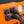 Two power cords plugged into AC outlets on an orange portable power station with a pressure gauge