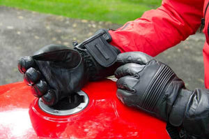 Warm and Safe black leather motorcycle gloves on a red fuel tank