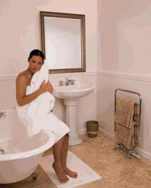 WarmRails freestanding towel warmer in a bathroom with a person holding a towel