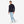 Man wearing a navy long sleeve quarter zip pullover with light blue jeans and white sneakers