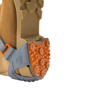 Winter Walking ice cleat attached to the heel of a tan boot
