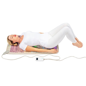 Person lying on a HealthyLine rainbow gemstone mat with a digital controller