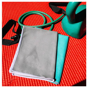 AlphaCool grey and teal cooling towels on a red exercise mat with fitness equipment