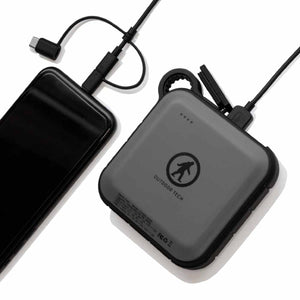 Outdoor Tech portable power bank charging a smartphone with a USB cable
