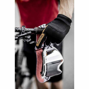 Hestra cycling glove on a hand holding mountain bike handlebars and goggles